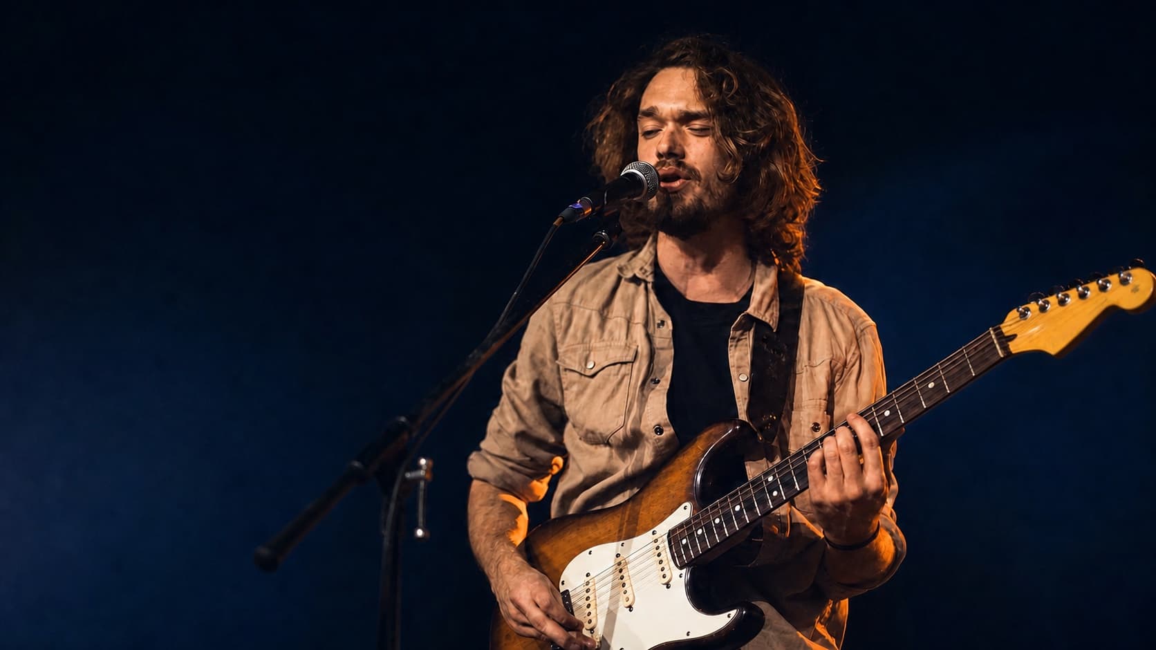 Gitarrist spielt eine deutlich sichtbare E-Gitarre auf einer Bühne