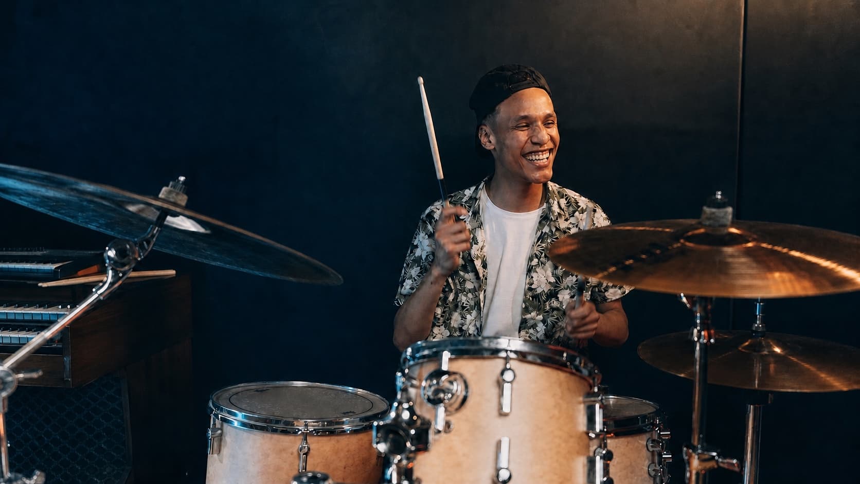 Lachender Schlagzeuger spielt an einem voll sichtbaren Drumset