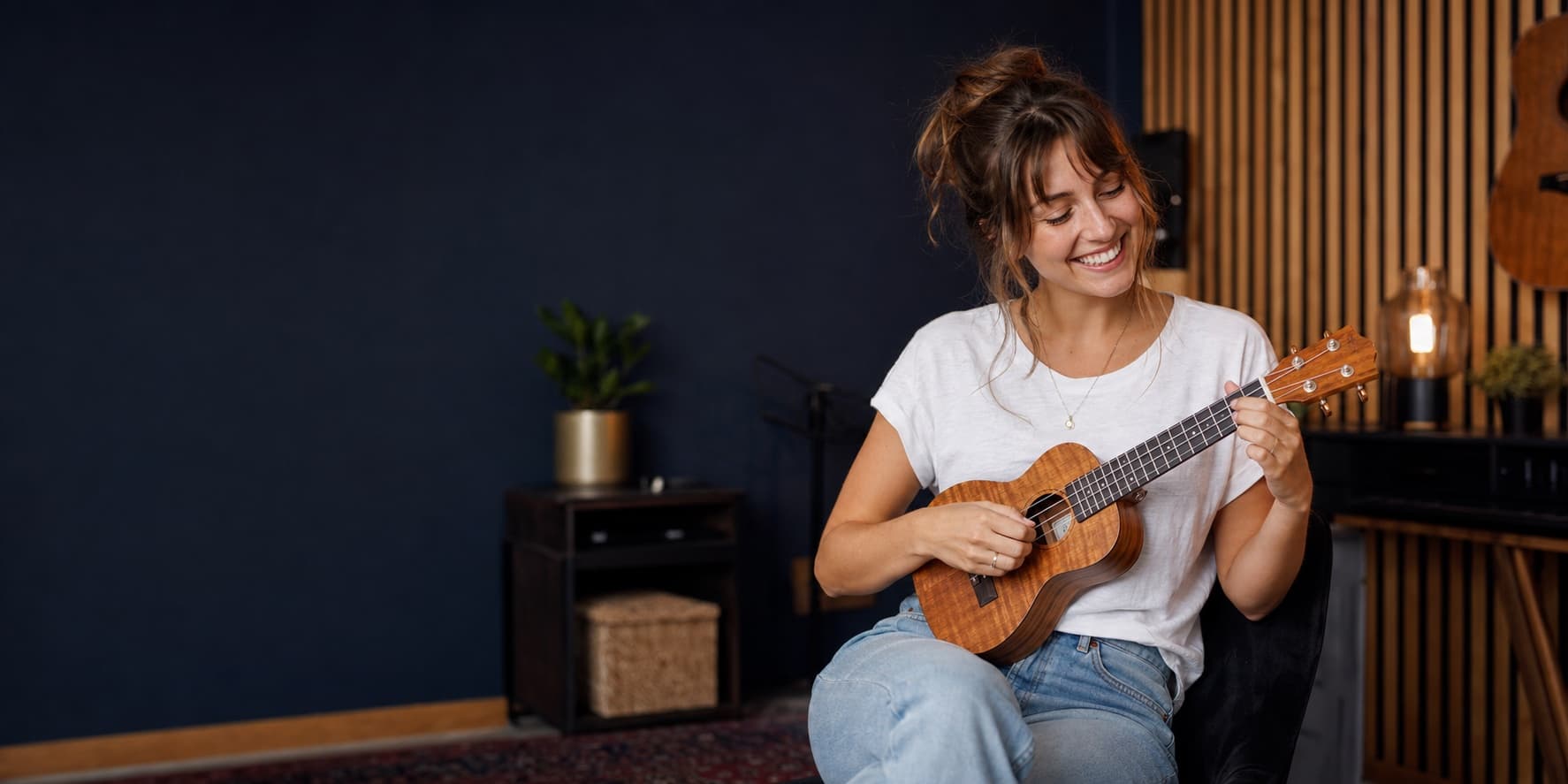 Glückliche Musikerin spielt eine deutlich sichtbare Ukulele im Musikstudio